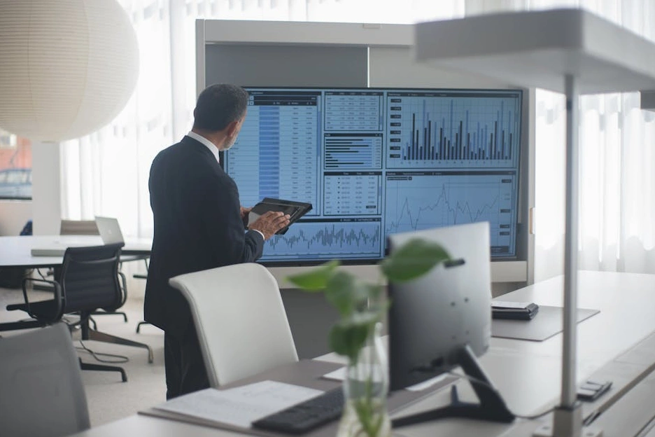 Tým konzultantů na schůzce analyzuje firemní data na obrazovce